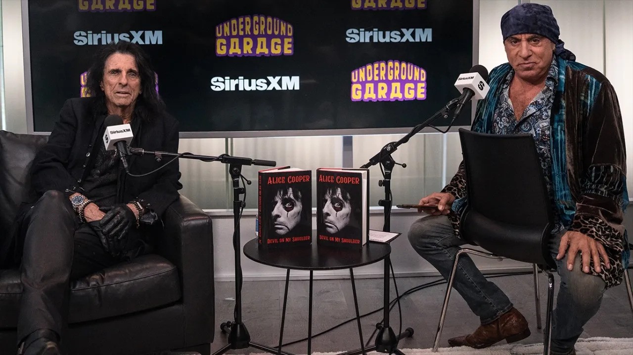 Alice Cooper and Steven Van Zandt sitting in a studio with two copies of Coopers book Devil on My Shoulder on a table between them. Listen to Underground Garage exclusively on SiriusXM Canada.